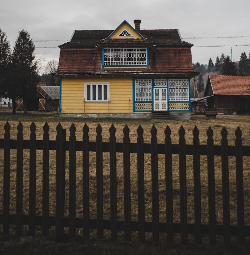 a yellow and blue house with a black fence
